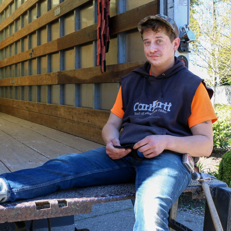 Second Use Employee Dash takes a break on the edge of the bed of a truck on a job site.