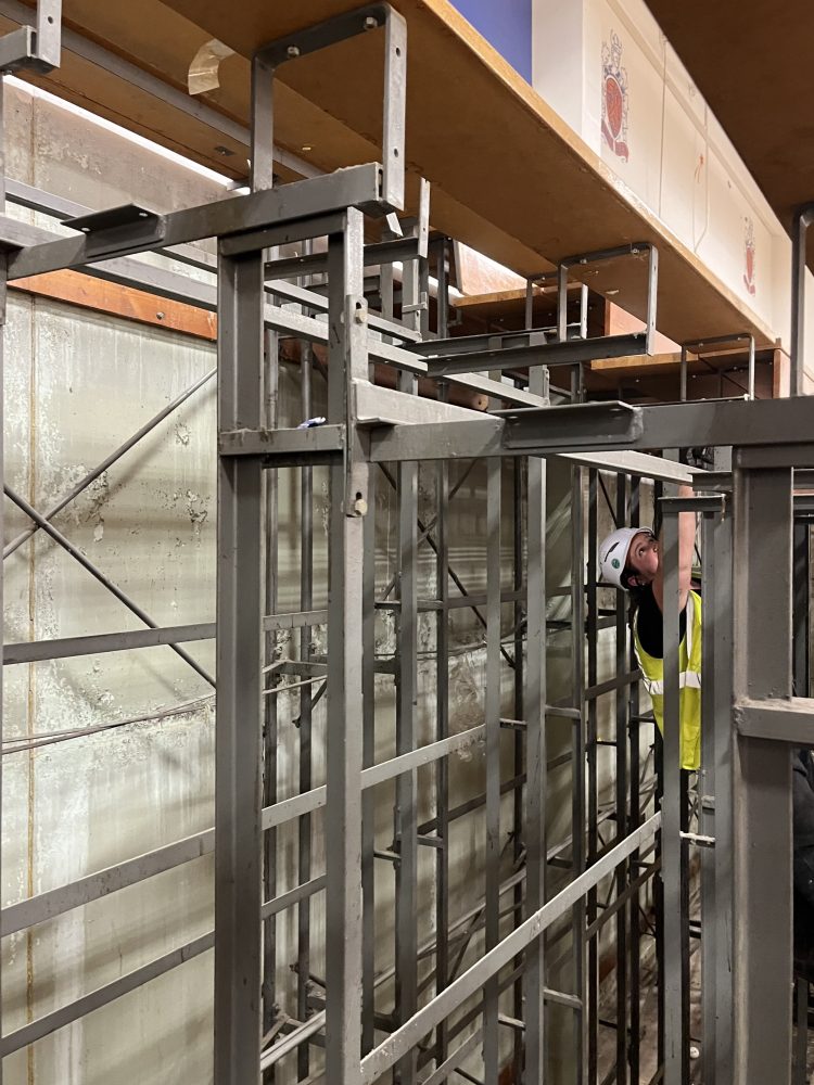 Person removing the bleacher boards while climbing in the metal structure